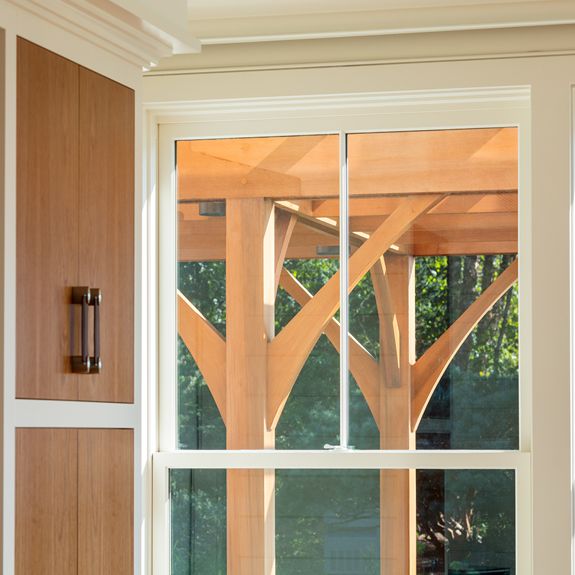 View of a curving cedar arbor out the window of a coastal shingle style home in Stonington, CT.
